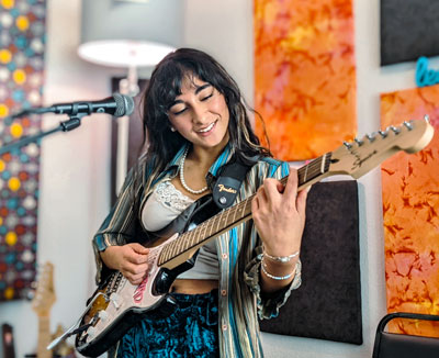 female indian student plays guitar in lesson room