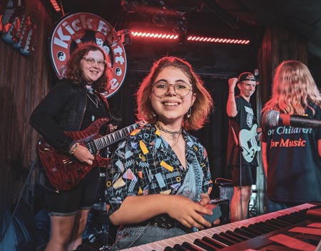 Student plays piano on stage in rock band