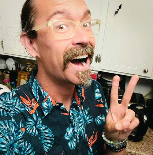 Bassist Bret Crow smiles and flashes a peace sign