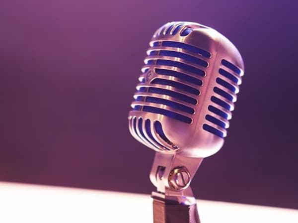 closeup of a vintage vocal microphone head against a blurred out purple background