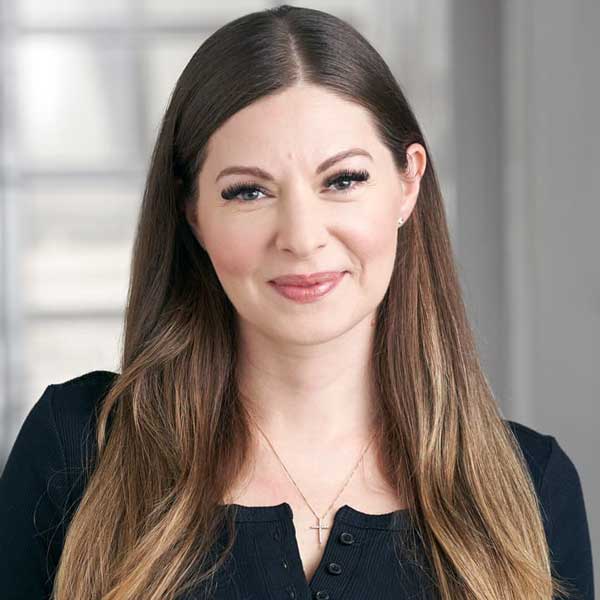 Female voice teacher with long brown hair smiles at the camera
